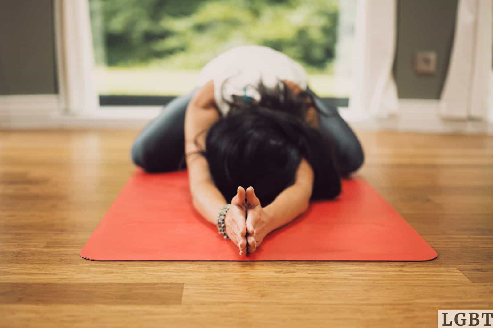 woman in white shirt lying on red mat on brown wooden table