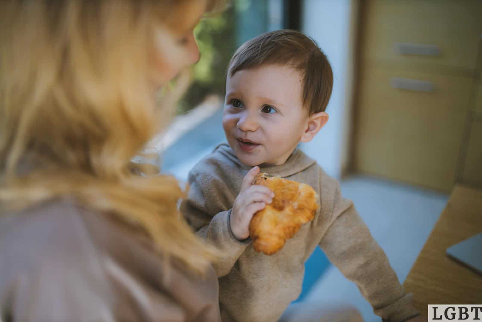 Baby Boy Eating a Croissant With his Mother